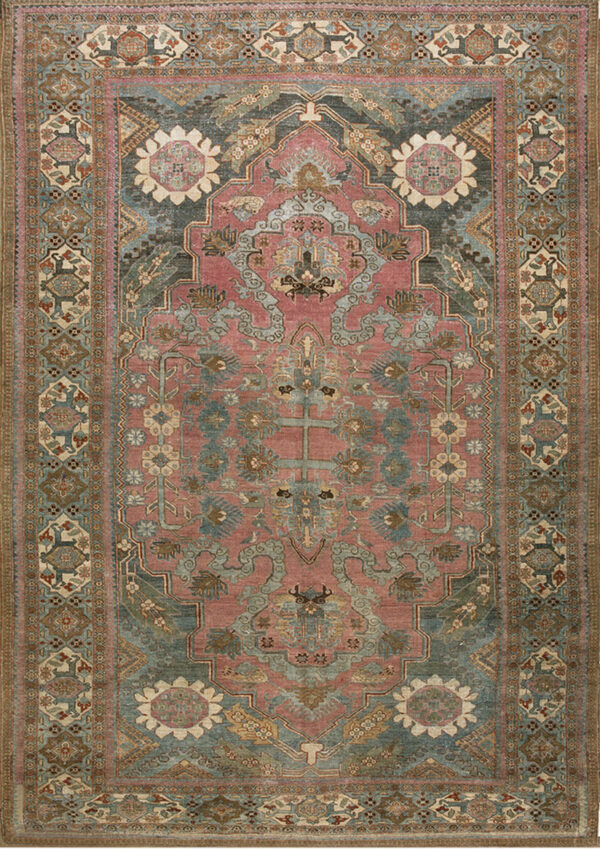 Low pile rug with a dusty rose field, muted blue-green medallion, and intricate floral and geometric patterns.