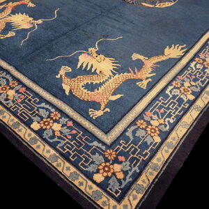 Dark blue rug with tan and pink dragon figures surrounded by ornate floral and fretwork borders.
