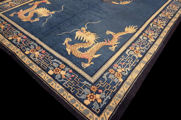 Dark blue rug with tan and pink dragon figures surrounded by ornate floral and fretwork borders.