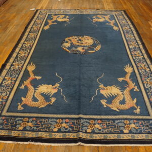 Blue dragon-patterned rug with gold and navy borders displayed on a wide plank hardwood floor.
