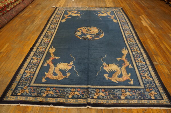 Blue dragon-patterned rug with gold and navy borders displayed on a wide plank hardwood floor.