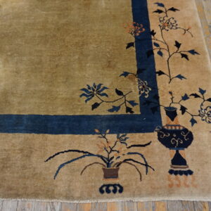 Beige high-pile rug border with navy blue floral vases on worn wooden floorboards.