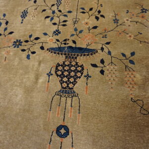 Plush golden-tan rug with a detailed navy blue vase and sprawling vines with peach and blue flowers.