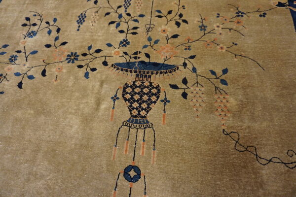 Plush golden-tan rug with a detailed navy blue vase and sprawling vines with peach and blue flowers.