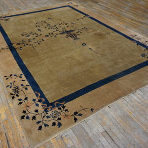 Muted gold rug with a central vase motif and blue floral borders rests on weathered wood planks.