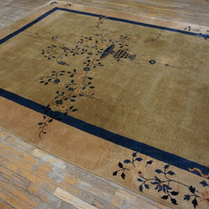 Lustrous olive rug with a blue border and delicate floral motifs covers rustic wood flooring.