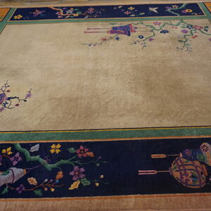 A large rug with a tan field and a wide navy border featuring colorful floral and lantern patterns.