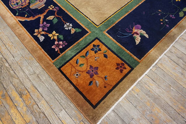 Tan, navy, green, and rust rug corner with a lush floral pattern lies on distressed wooden flooring.