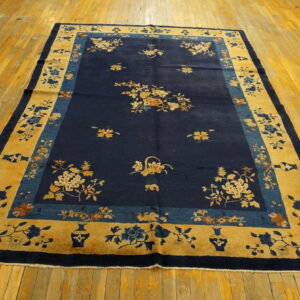 Rectangular blue and gold rug with ornate floral patterns displayed on distressed hardwood floors.