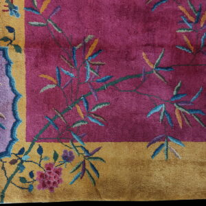 Magenta rug field featuring bamboo stalks and flowers, bordered by gold and stylized purple motifs.