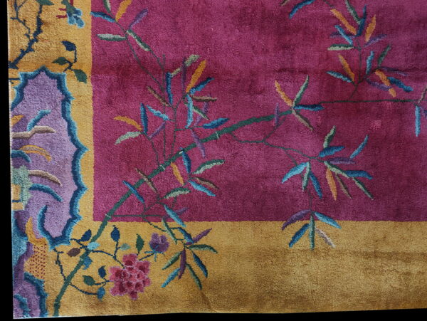 Magenta rug field featuring bamboo stalks and flowers, bordered by gold and stylized purple motifs.