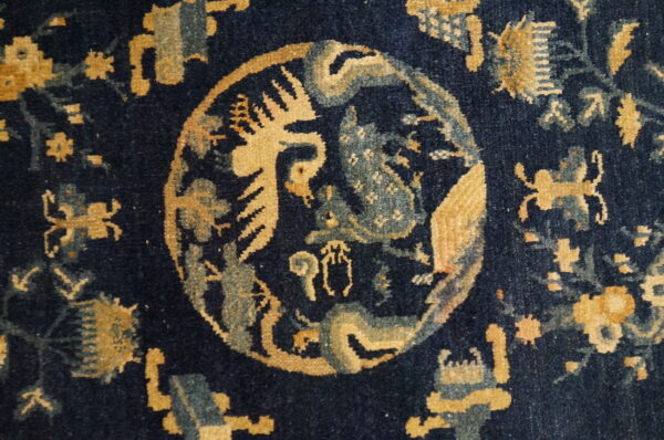 Navy blue rug detail showing an intricate central medallion pattern in gold and muted blue.