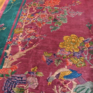 Magenta rug with teal border showcases a multicolored scenic pattern including flowers and a blue bird on wood floor.