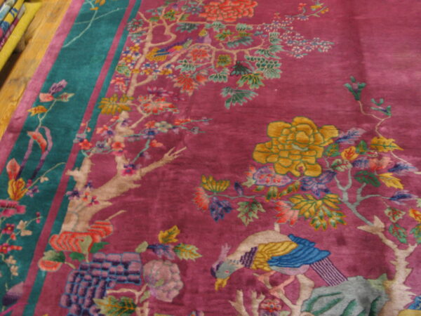 Ornate magenta rug featuring colorful tree, flower, and bird motifs on wood floor.