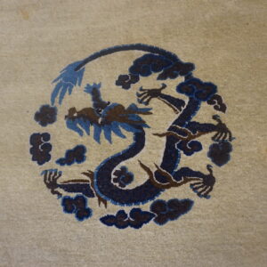 A low-pile beige rug features a circular dark blue and brown stylized dragon motif surrounded by clouds.