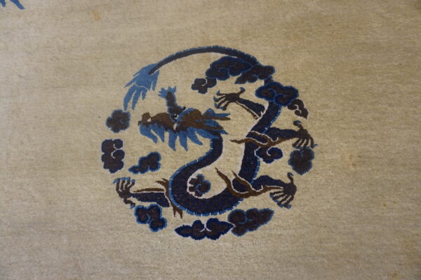 A low-pile beige rug features a circular dark blue and brown stylized dragon motif surrounded by clouds.