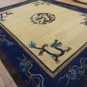 Yellowish-beige rug with blue and brown stylized dragon patterns on a rustic wooden floor.
