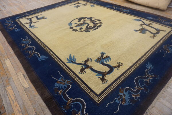 Yellowish-beige rug with blue and brown stylized dragon patterns on a rustic wooden floor.