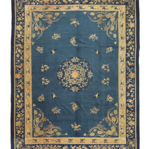 Rectangular dark blue rug featuring a central gold floral medallion and complex multi-layered vine and flower borders.