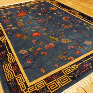 Navy blue rug with scattered red and gold floral vines, framed by a gold key border on wood flooring.