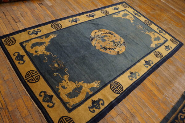 Teal rug with central medallion and gold dragon borders rests on plank wood floor.