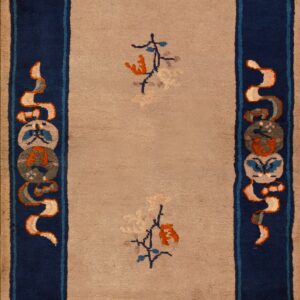 Rectangular tan and navy rug featuring medallions, lying on distressed wood flooring.