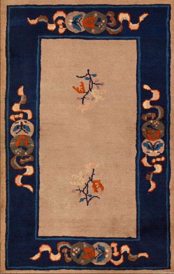 Rectangular tan and navy rug featuring medallions, lying on distressed wood flooring.