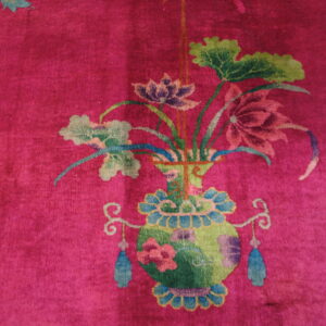 Vibrant magenta rug displaying a colorful floral bouquet in a green and blue decorative vase.