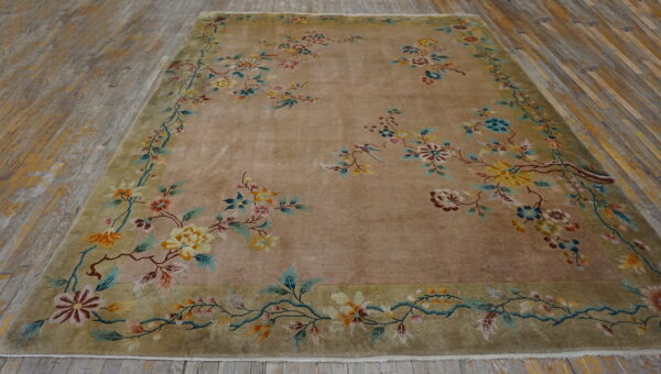 Tan field rug with sprawling multicolored floral vines and a wide sage border on gray wood flooring.