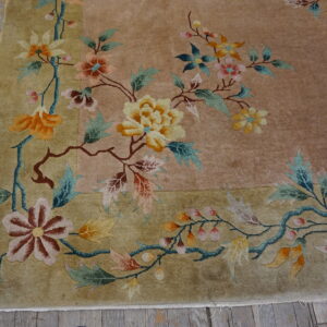 Muted floral rug with orange, pink, and teal botanical designs on tan and khaki fields.
