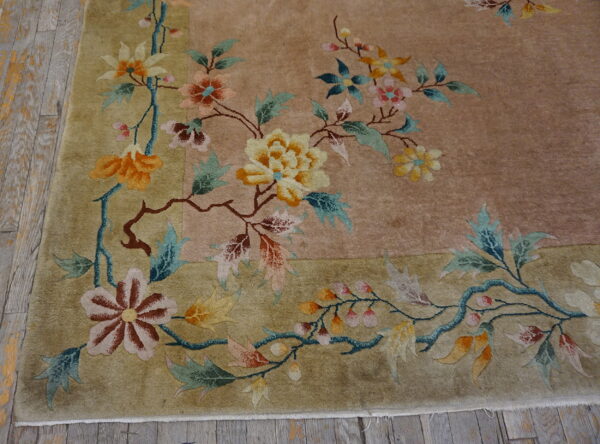 Muted floral rug with orange, pink, and teal botanical designs on tan and khaki fields.