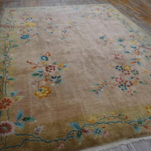 Taupe plush rug with colorful floral sprays and olive border lying on weathered wood flooring.