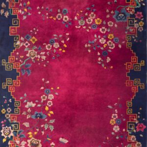 A deep magenta rug displays large flowering tan vines next to a navy border with a geometric gold key pattern.