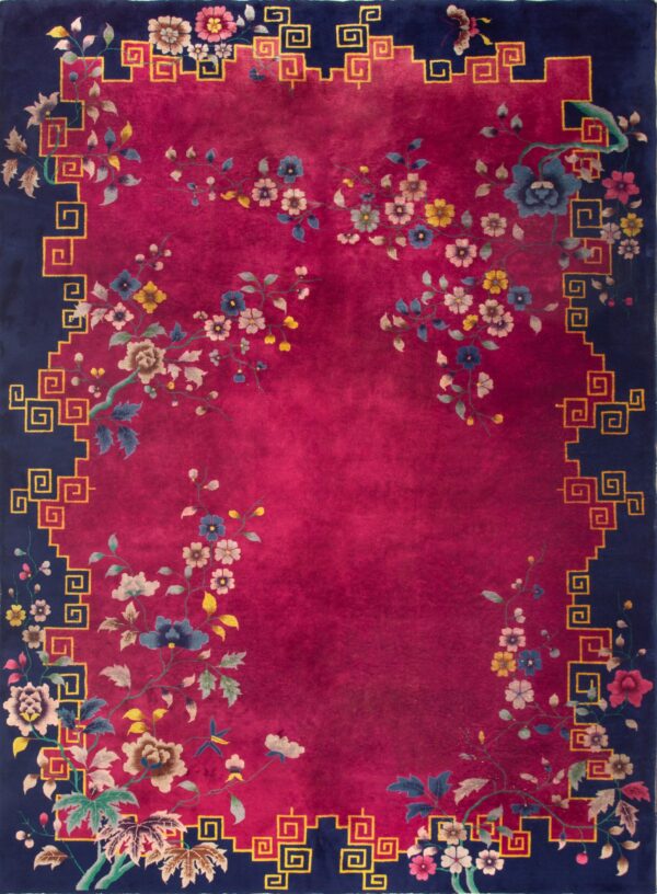 A deep magenta rug displays large flowering tan vines next to a navy border with a geometric gold key pattern.