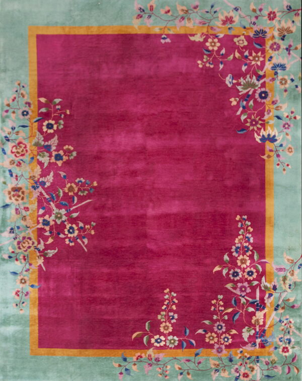 Magenta rug with a seafoam green border framed by gold, featuring detailed multicolored floral patterns.