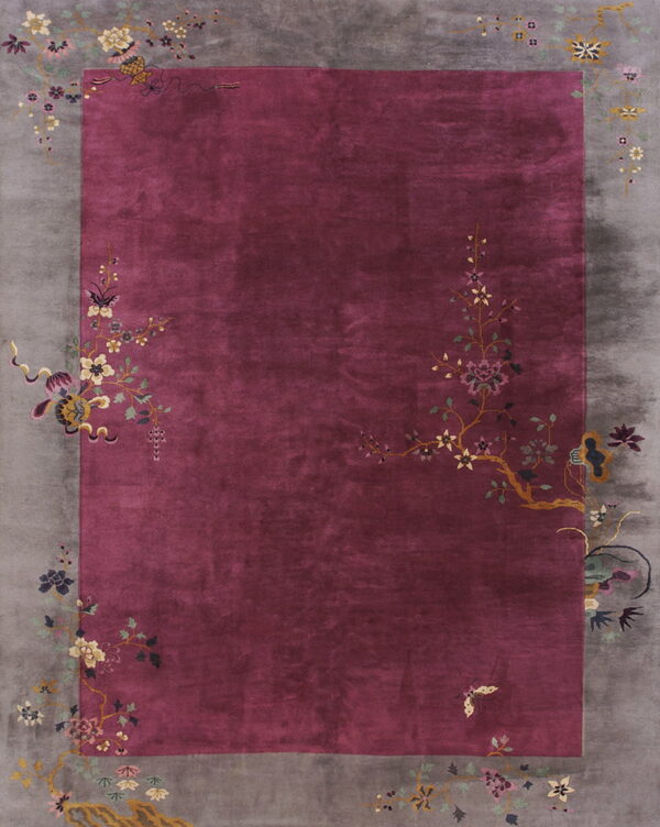 A velvety magenta rug with a wide gray border decorated with multicolor floral and butterfly patterns.