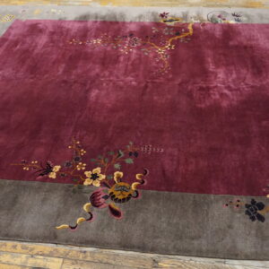 Deep reddish-purple rug with a contrasting gray border featuring multicolored floral and creature motifs.