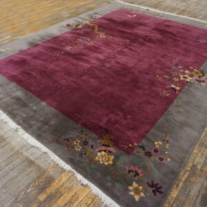 High-pile rug featuring a magenta field and gray border with multicolored floral patterns on rustic wood.