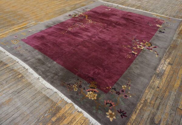 High-pile rug featuring a magenta field and gray border with multicolored floral patterns on rustic wood.