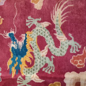 Magenta rug detail showing short pile and colorful dragons patterned in pale green, blue, and yellow.