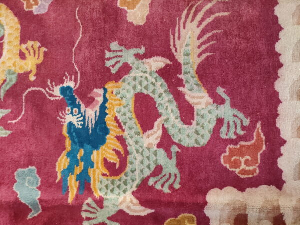 Magenta rug detail showing short pile and colorful dragons patterned in pale green, blue, and yellow.