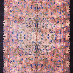 Rosy pink field rug with dense blue and green floral designs, framed by a thick solid black border.