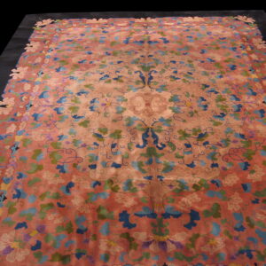 Large coral rug with intricate blue, green, and pink floral patterns and a distinctive cut-out border.