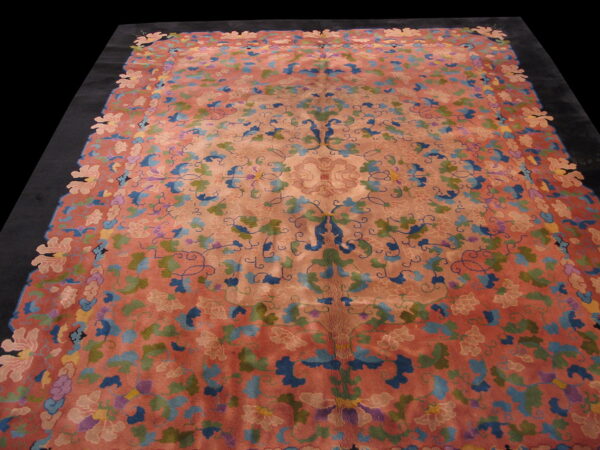 Large coral rug with intricate blue, green, and pink floral patterns and a distinctive cut-out border.