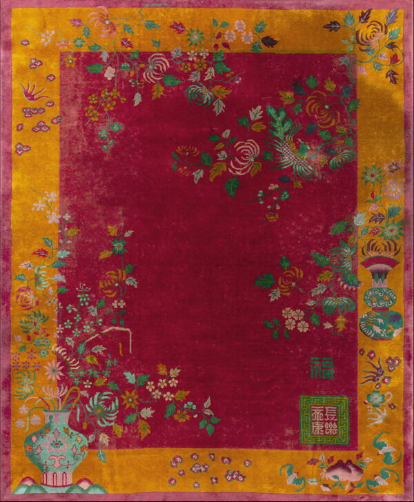 Magenta rug with a gold border features intricate floral sprays, vases, birds, and subtle chinese characters.