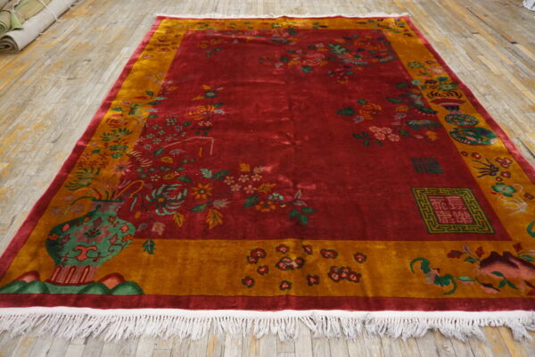 High-pile red and gold rug featuring detailed floral motifs and vases, displayed on wood flooring.