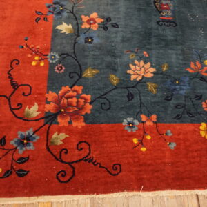 Deep blue floral rug border in rust red on yellow wooden floorboards.