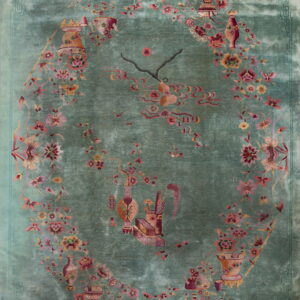 Velvety teal rug displaying pink and red florals, vines, and symbolic vessels within a central oval.