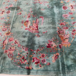 Distressed teal rug with rose and peach floral sprays lies on a bright, white tile floor.