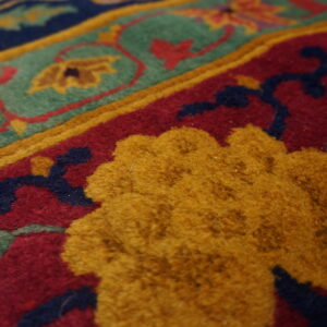 Detail of a high-pile rug with raised yellow, deep red, teal, and navy patterned sections.